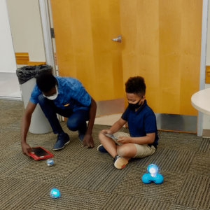 researcher and child playing with robots on the ground